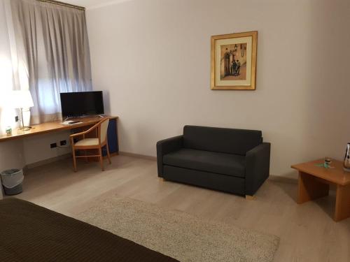 a living room with a couch and a desk with a computer at Roero Park Hotel in Sommariva Perno