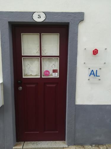 a red door with a clock on top of it at Casa do Ti Messias in Almeida