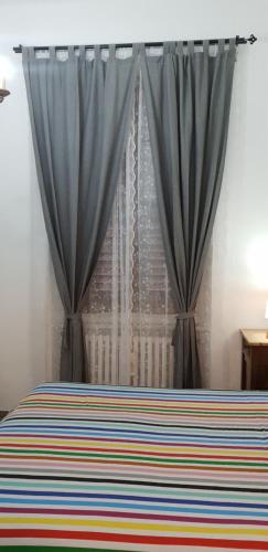 een slaapkamer met een bed met blauwe gordijnen en een raam bij APPARTAMENTI DEI MILLE in Novi Ligure