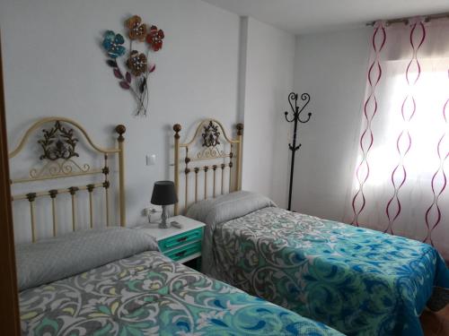 a bedroom with two beds and a table with a lamp at Casas los Rosales in Guadix