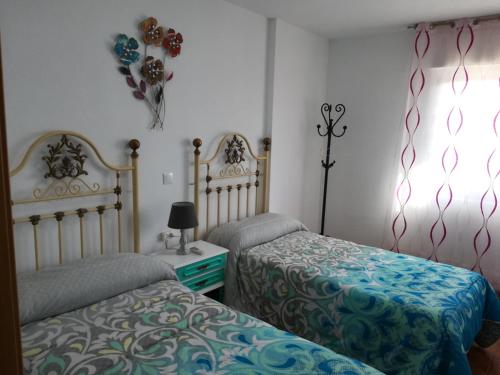 グアディクスにあるCasas los Rosalesのベッドルーム1室(ベッド2台、ランプ付きテーブル付)