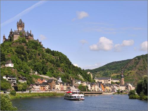 a boat on a river in front of a mountain at Gast und Weinhof Beim Schneemann in Valwig