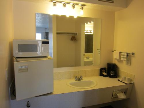 a bathroom with a sink and a microwave on a counter at Peace Villa Motel in Dawson Creek