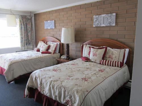 a bedroom with two beds and a brick wall at Peace Villa Motel in Dawson Creek