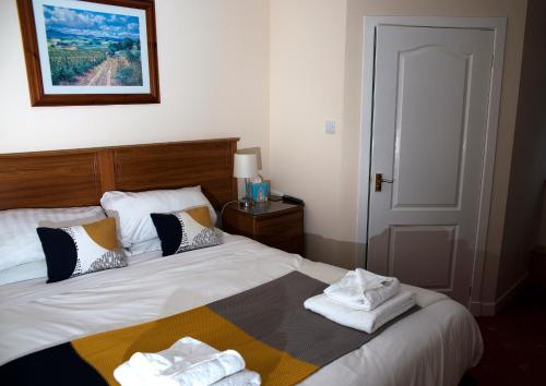 1 dormitorio con 1 cama con toallas en Herdshill Guest House, en Wishaw