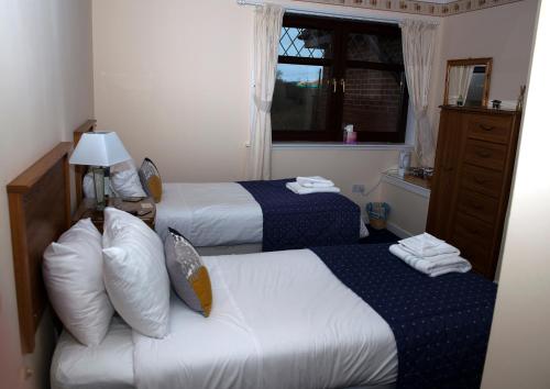 a hotel room with two beds and a window at Herdshill Guest House in Wishaw