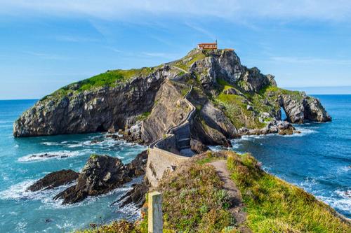 a house on top of a rocky island in the ocean at APARTAMENTOs URDAIBAI 1 in Bermeo