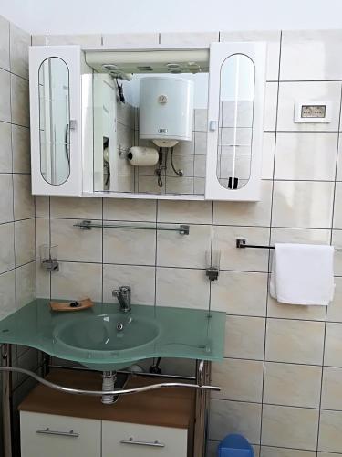 a bathroom with a green sink and mirrors at Apartman Rosanda 1 in Premuda