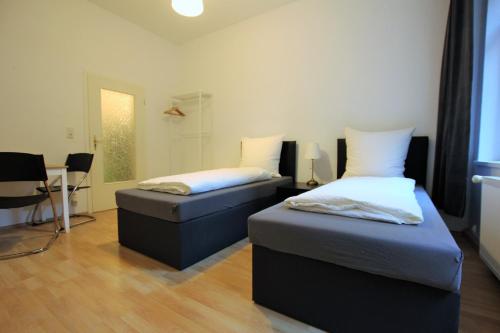 a bedroom with two beds and a table and a desk at 2-room apartment in Hannover