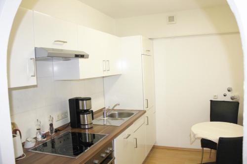 eine kleine weiße Küche mit einem Waschbecken und einem Tisch in der Unterkunft Ferienwohnung Stett in Meersburg