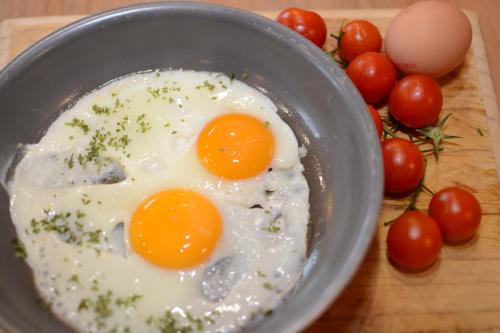 two eggs in a bowl next to tomatoes on a cutting board at Das kleine, feine SONNWEND in Alpbach