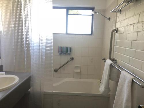 a bathroom with a bath tub and a sink at Allan Cunningham Motel in Toowoomba
