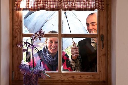 dwóch mężczyzn patrzących przez okno z parasolką w obiekcie Agritur Maso Pra' Cavai B&B w mieście Balbido-rango