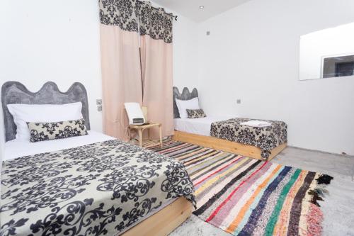 a bedroom with two beds and a rug at Hôtel familiale les grotte in Aït Ben Haddou