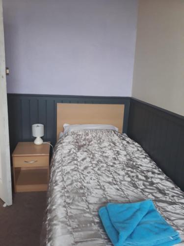 a bedroom with a bed with a blue towel on it at Llwynygog Guest House in Aberystwyth