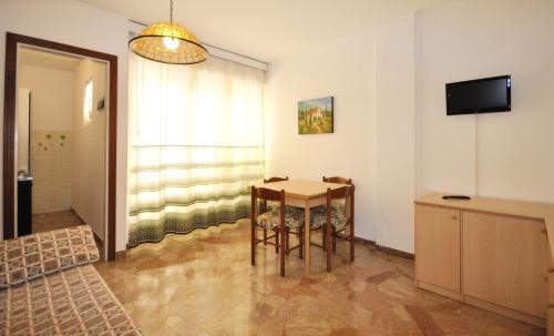 una camera con tavolo, sedie e televisore di Condominio Aurora a Bibione