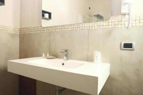 
a white sink sitting under a mirror in a bathroom at Albergo Maccotta in Trapani
