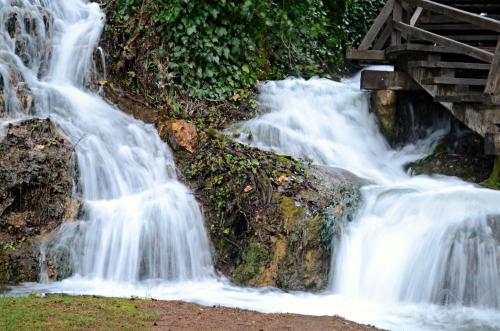 a waterfall on the side of a mountain with a bridge at Samodol in Drinovci