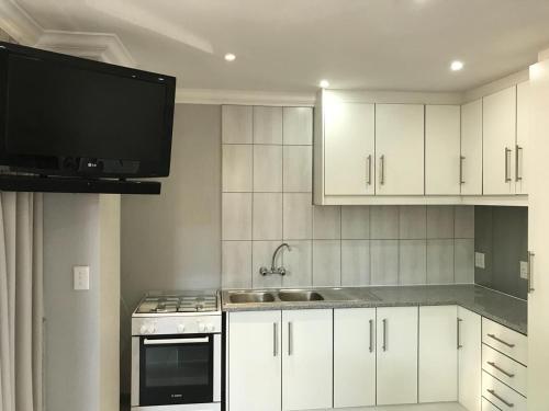 uma cozinha com armários brancos e uma televisão de ecrã plano em 5 on Pieter Hugo em Paarl