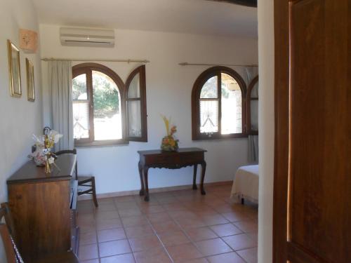 uma sala de estar com uma mesa e duas janelas em B&B L' Incantu em Santa Teresa Gallura