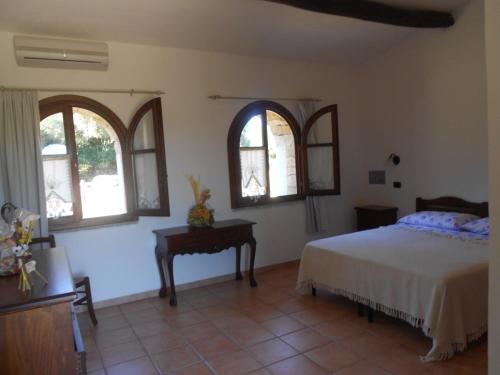 um quarto com uma cama, uma mesa e janelas em B&B L' Incantu em Santa Teresa Gallura