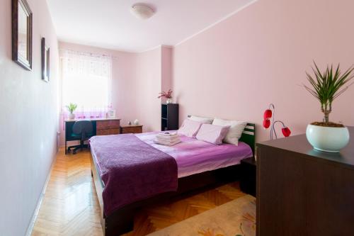 a bedroom with a bed with a purple blanket at Apartment City center in Novi Sad