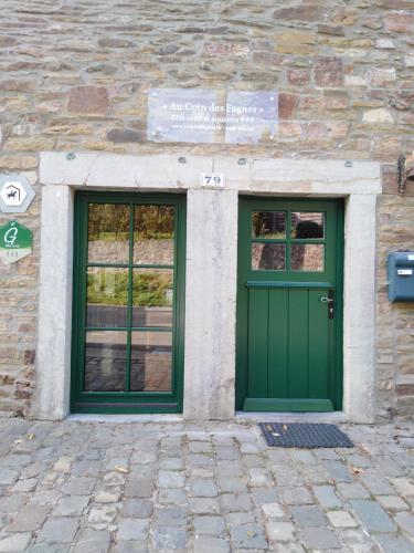a green door and two windows on a stone building at Au Coin des Fagnes in Jalhay