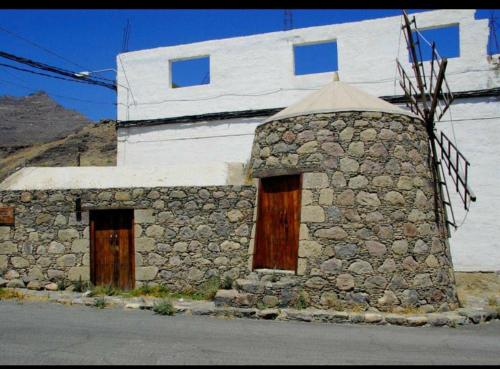a stone building with wooden doors and a stone pillar at Alojamiento la Real in La Aldea de San Nicolas