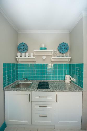 a kitchen with a sink and a blue tile wall at Apartment Batumi Weekend in Batumi