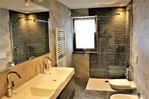 a bathroom with a sink and a toilet and a mirror at Alpenappart in Cadipietra