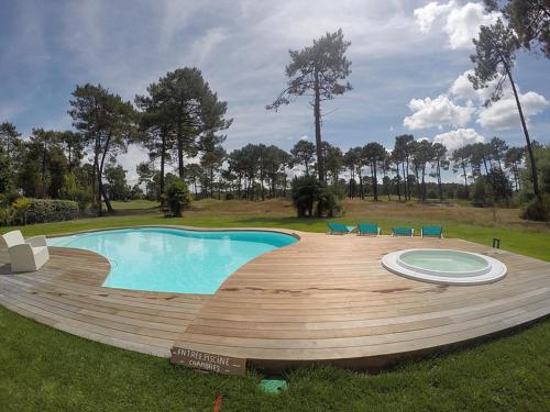 une grande piscine entourée d'une terrasse en bois. dans l'établissement Villa BORA BORA, à Gujan-Mestras