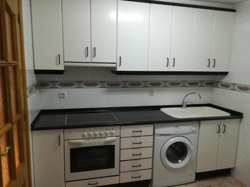 - une cuisine avec des placards blancs et un lave-linge dans l'établissement Apartamento La Muralla de Teruel, à Teruel
