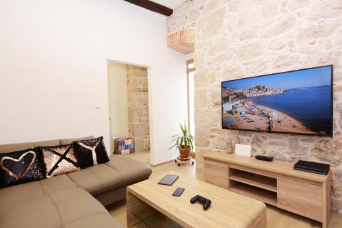 a living room with a large flat screen tv on a stone wall at XY Suites - Design Apartments in Šibenik