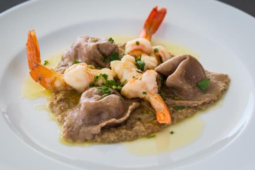 a white plate of food with shrimp and meat at Alkistis Beach Hotel - Adults Only in Agios Stefanos