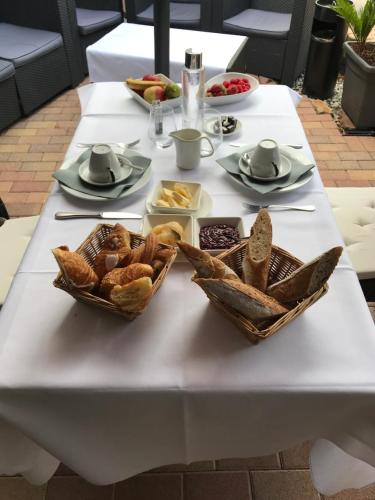 a white table with bread and pastries on it at Hôtel Au Petit Pont in La Wantzenau