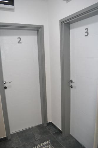 two white doors with numbers on them in a room at Smestaj Pandora Sobe sa kupatilom in Jagodina