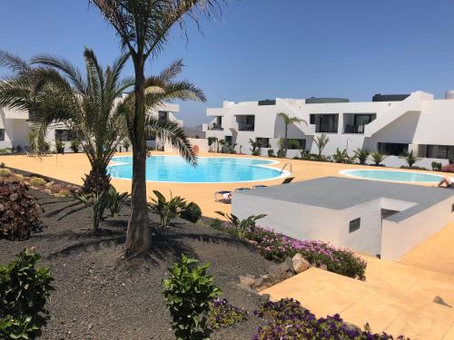 a resort with two pools and palm trees and white buildings at Beach Life in Villaverde