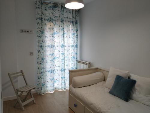 a bedroom with a bed with a chair and a window at Apartamento OD in Piedras Blancas