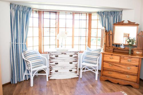 een kamer met een dressoir, 2 stoelen en een spiegel bij Chikanka in Himeville