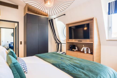 a bedroom with a large bed with a flat screen tv at MADISON Saint Jean de Luz - Handwritten Collection in Saint-Jean-de-Luz