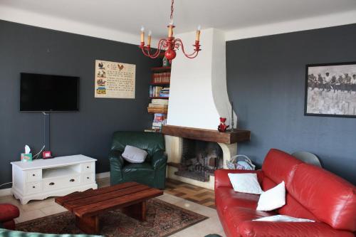 a living room with a red couch and a chair at Les 2 Granges Gîte in Bérig-Vintrange