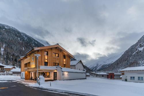 un bâtiment sous la neige avec des montagnes en arrière-plan dans l'établissement Hochstatt Appartements, à Sölden