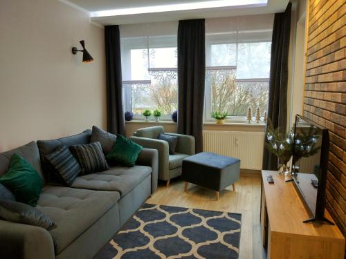 ein Wohnzimmer mit einem Sofa und einem Stuhl in der Unterkunft Apartament Zielono Mi in Kołobrzeg