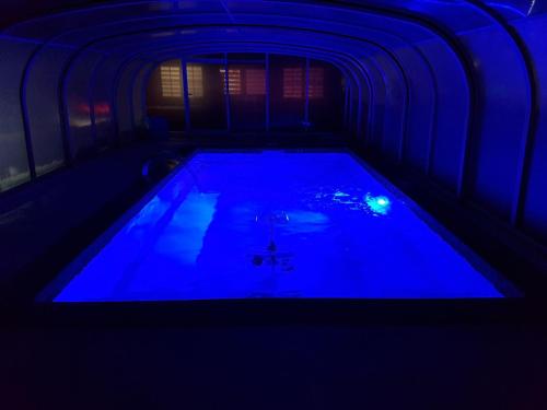 a swimming pool in a dark room with blue lighting at Chambre d'hôtes source de la St Baume in Plan dʼAups