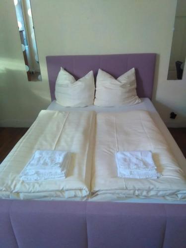 a large bed with white sheets and pillows at Doppelbettzimmer mit Bad in Kaiserslautern