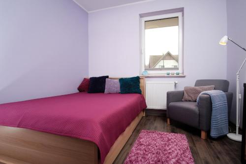 a bedroom with a bed and a chair and a window at apt. ALTERNATYWA in Żarnowska