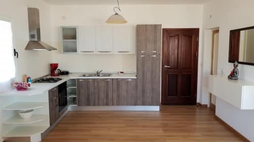 a kitchen with white cabinets and a wooden door at Beachhaus Praia de Chaves in Cabeçadas