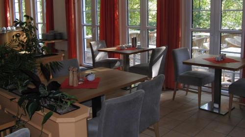 a restaurant with tables and chairs and windows at Parkstadthotel Bad Muskau in Bad Muskau