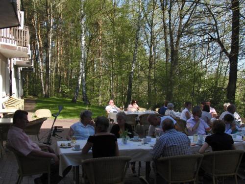 a group of people sitting at tables in a yard at Parkstadthotel Bad Muskau in Bad Muskau