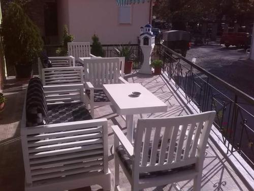 a group of white chairs and a table on a balcony at Guest House Sakis. in Órma